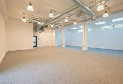 Spacious open-plan workspace with industrial exposed ductwork and pendant lighting.