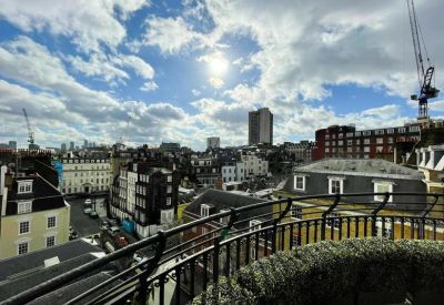 Rooftop terrace overlooking London city skyline with a curved black railing.