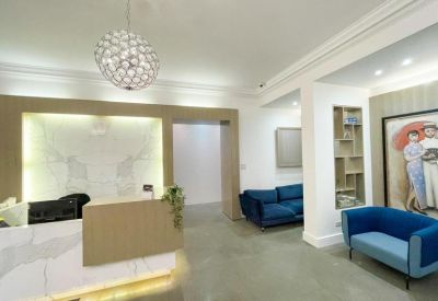 Modern reception lobby with marble desk, spherical pendant light, and blue velvet sofas.