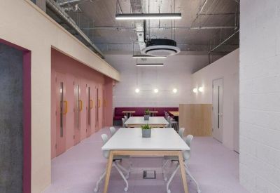 Modern corridor and workspace with pink walls and long white tables.