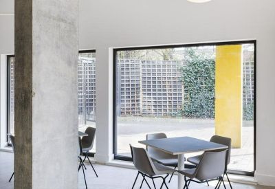 Meeting area with grey chairs, a square table, and a large window overlooking a garden.