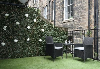 Outdoor patio area with artificial grass and black wicker seating.