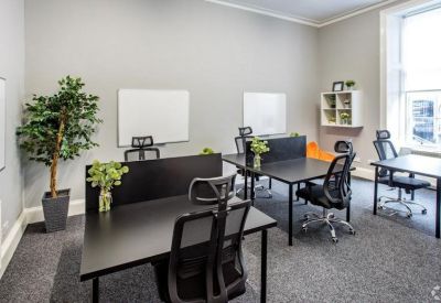 Open-plan office with black desks, mesh chairs, and potted plants.