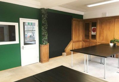 Spacious workspace featuring dark tables, green feature walls, and wood-paneled cabinetry.