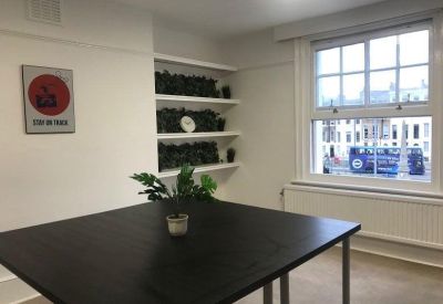 Bright meeting room with a large dark wood table and built-in shelving with plants.