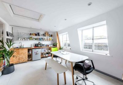 Communal kitchen and dining area with light wood cabinetry and a skylight.