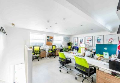 Bright open-plan office featuring several desks with vibrant lime green ergonomic chairs.