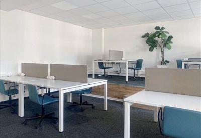 Modern open-plan workspace with white desks and teal chairs.