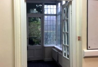 Bright office doorway looking into a sunlit conservatory area.