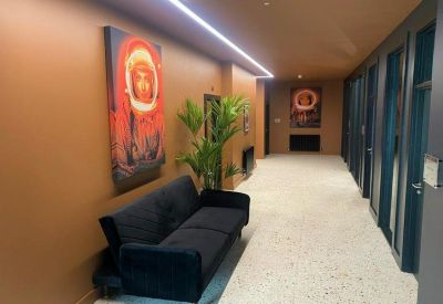 Modern hallway with warm lighting, a plush navy sofa, and space-themed wall art.