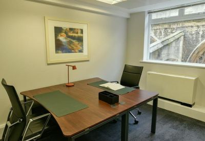 Private office with a two-person wooden desk and a framed nature print.