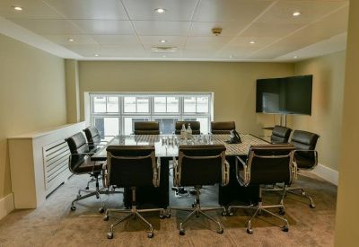Executive boardroom with a marble-top table, black leather chairs, and a wall-mounted screen.