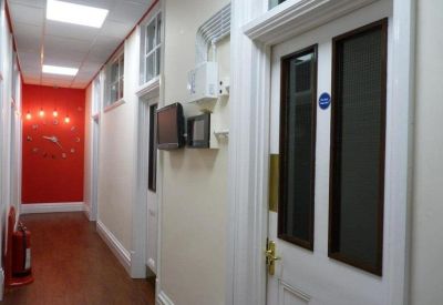 Narrow office corridor with a bright red feature wall and wood flooring.