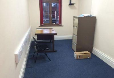 Small private office with a wooden desk and filing cabinet.