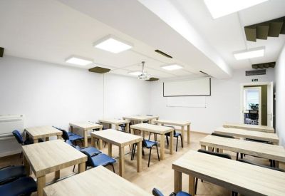 Classroom-style training room with rows of wooden tables and blue chairs.