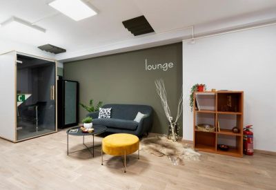 Relaxing lounge area featuring an olive green wall, grey sofa, and yellow velvet ottoman.