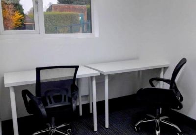 Bright private office featuring two white desks and black mesh ergonomic chairs.