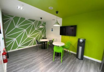 Breakout area with a green geometric feature wall and modern cafe tables.