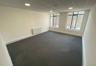 Spacious, empty private office suite with grey carpeting and large windows.