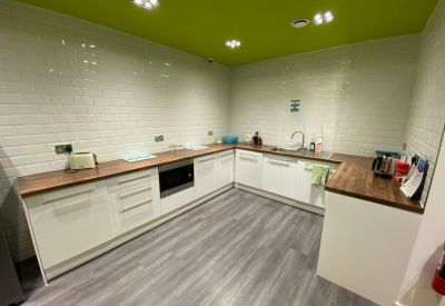 Modern communal kitchen with white cabinetry, wood-effect countertops, and a green ceiling.