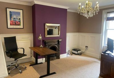 Private office space with a standing desk, ergonomic chair, and decorative purple chimney breast.