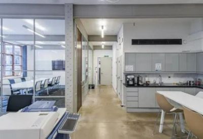 Minimalist kitchen and break area with grey cabinetry and a white breakfast bar.