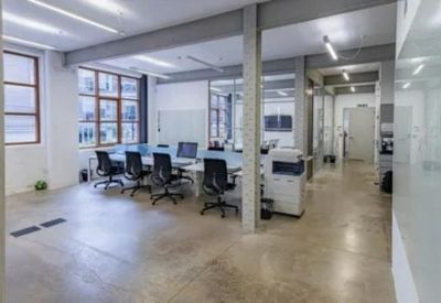 Bright open-plan workspace with multiple desks and large windows.