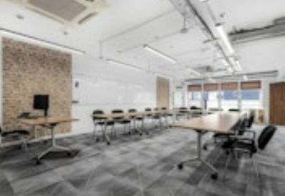 Long meeting table with black chairs in a room featuring a textured accent wall.