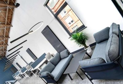 Modern lounge area featuring grey sofas, a coffee table, and large windows.