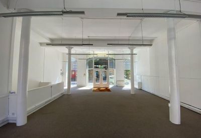 Spacious open-plan office with white pillars and hanging linear lighting.