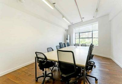Bright meeting room with a large white table, black mesh chairs, and large windows.