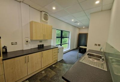 Staff kitchen and breakout area with light wood cabinetry and grey countertops.