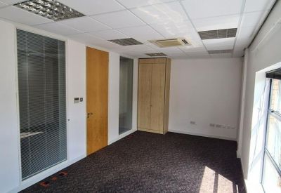 Private office suite with a wood-finish door and dark grey carpeting.