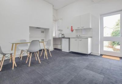 Kitchenette and dining area with grey chairs and dark blue carpeting.