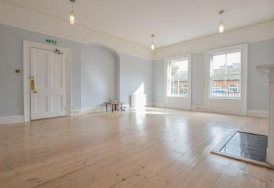 Large office space with light blue walls and polished light wood floors.
