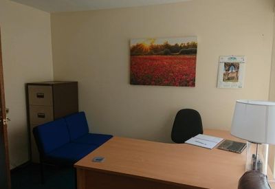 Private office featuring a wooden desk, blue sofa, and colorful wall art.