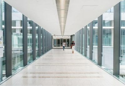 Bright, modern glass-walled corridor with a central ceiling skylight.