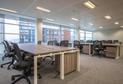 Professional office floor with rows of wooden desks and black mesh ergonomic chairs.