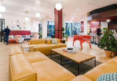 Spacious communal lounge featuring yellow leather sofas, a foosball table, and warm lighting.