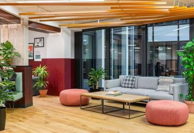 Breakout area with a grey sofa, pink ottomans, and decorative wooden ceiling slats.
