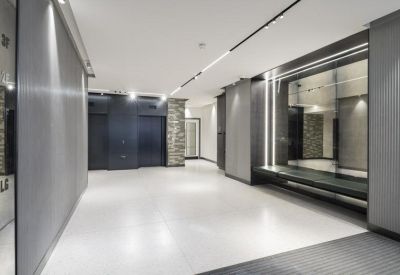 Modern reception area with polished white floors, dark wood paneling, and integrated strip lighting.