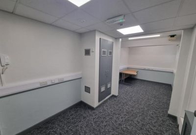 Small office space with grey carpeting and a wooden desk in the background.