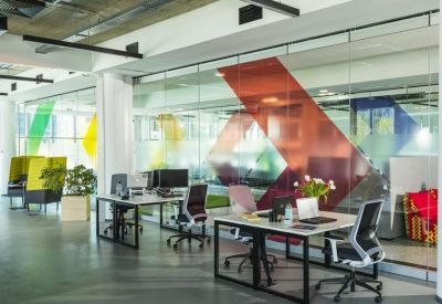 Bright, open-plan workspace with colorful geometric wall graphics and modern desks.