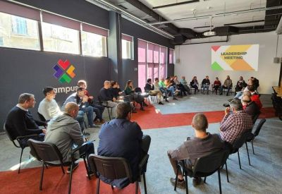Large meeting space with people seated in a circle for a leadership workshop.