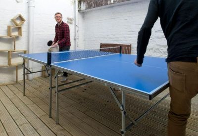 Spacious communal breakout area with a blue ping pong table on a wooden deck.