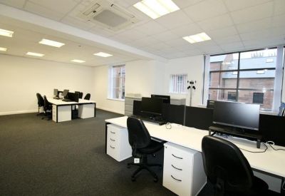 Bright workspace featuring multiple workstations with monitors and large windows overlooking the street.