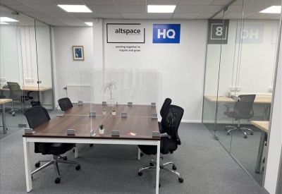 Brightly lit open-plan office with a central wooden desk and glass partitions.