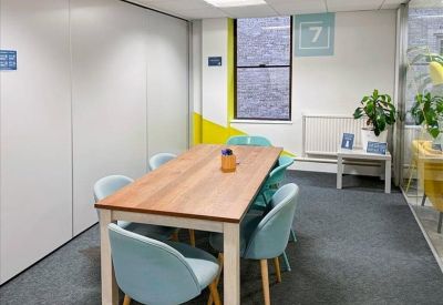 Vibrant meeting room with light blue chairs and a yellow accent wall.