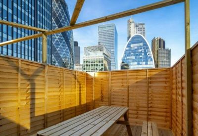 Outdoor wooden terrace with a picnic table overlooking iconic city skyscrapers.