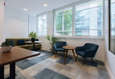 Bright breakout lounge with blue velvet armchairs and a green velvet banquette.